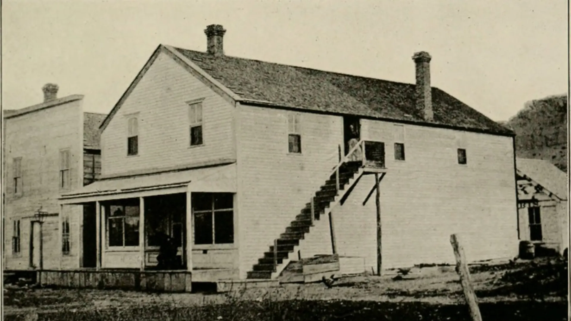A two-story frame store building with an outside staircase to the upper floor.