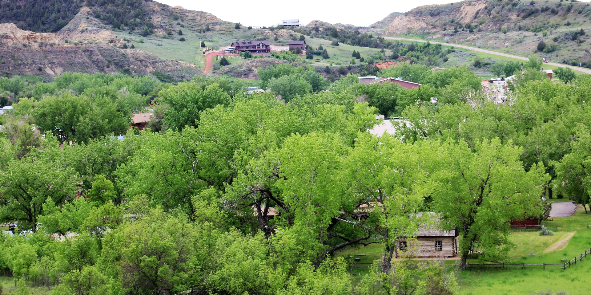 The town of Medora among green cottonwoods, with Badlands buttes rising behind