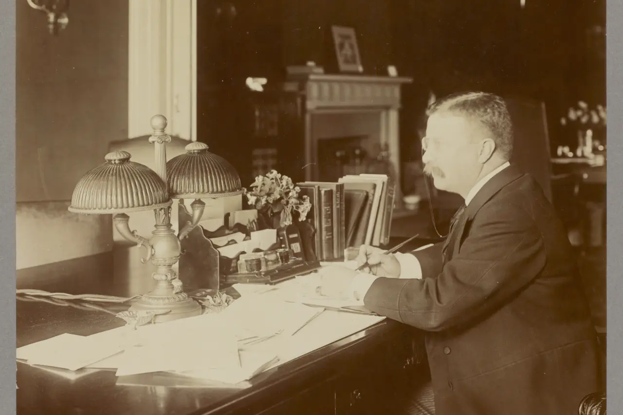 Photograph of Theodore Roosevelt sitting at a desk