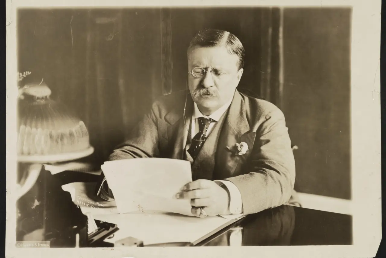 Theodore Roosevelt sitting at desk