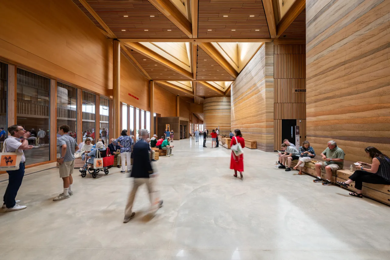Visitors walking through the warm wood-paneled great hall of the Theodore Roosevelt Presidential Library