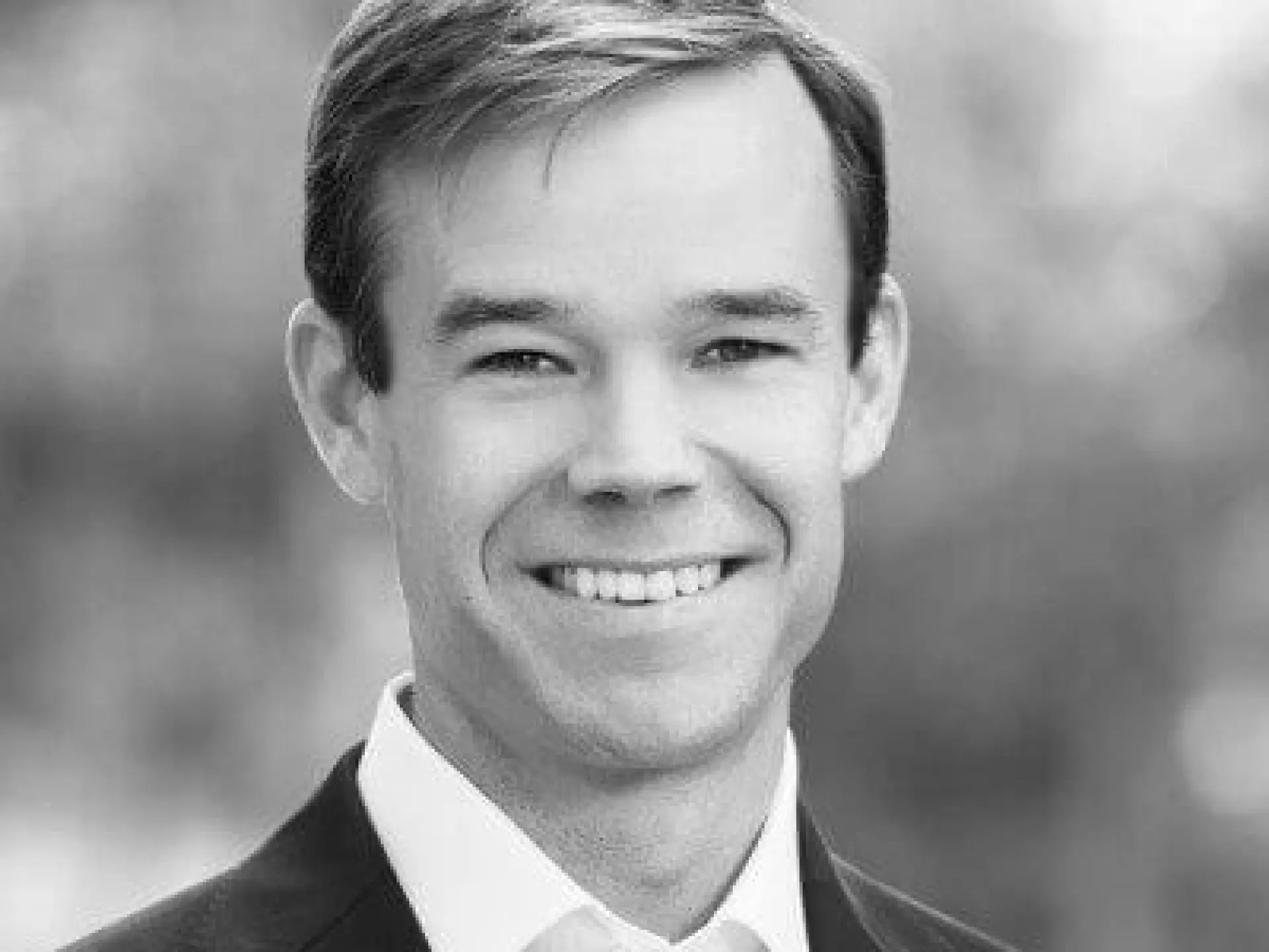Smiling man in a suit, black and white photograph.