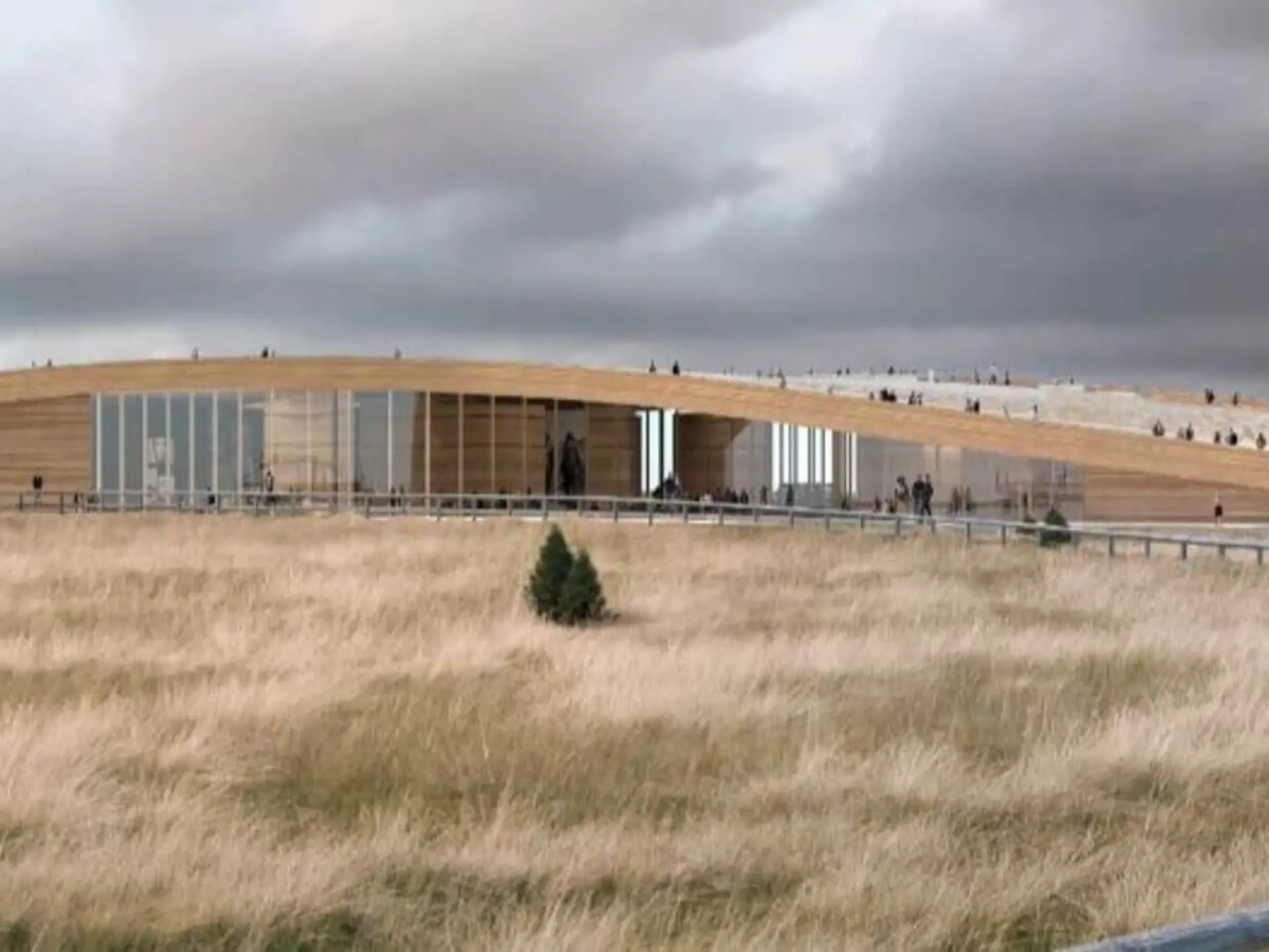 Modern building with wooden roof on grassy landscape, under cloudy sky.