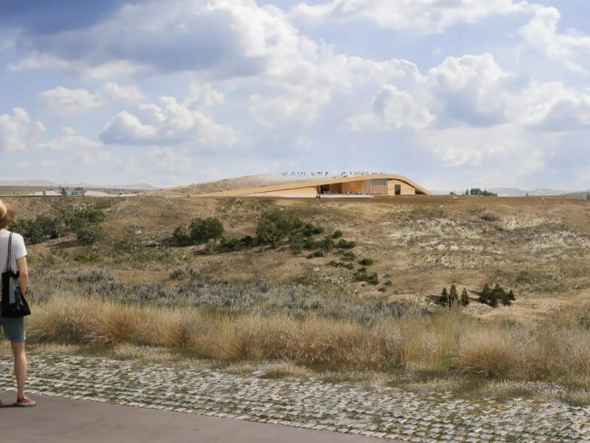 Two people overlook a grassy landscape under a cloudy sky.