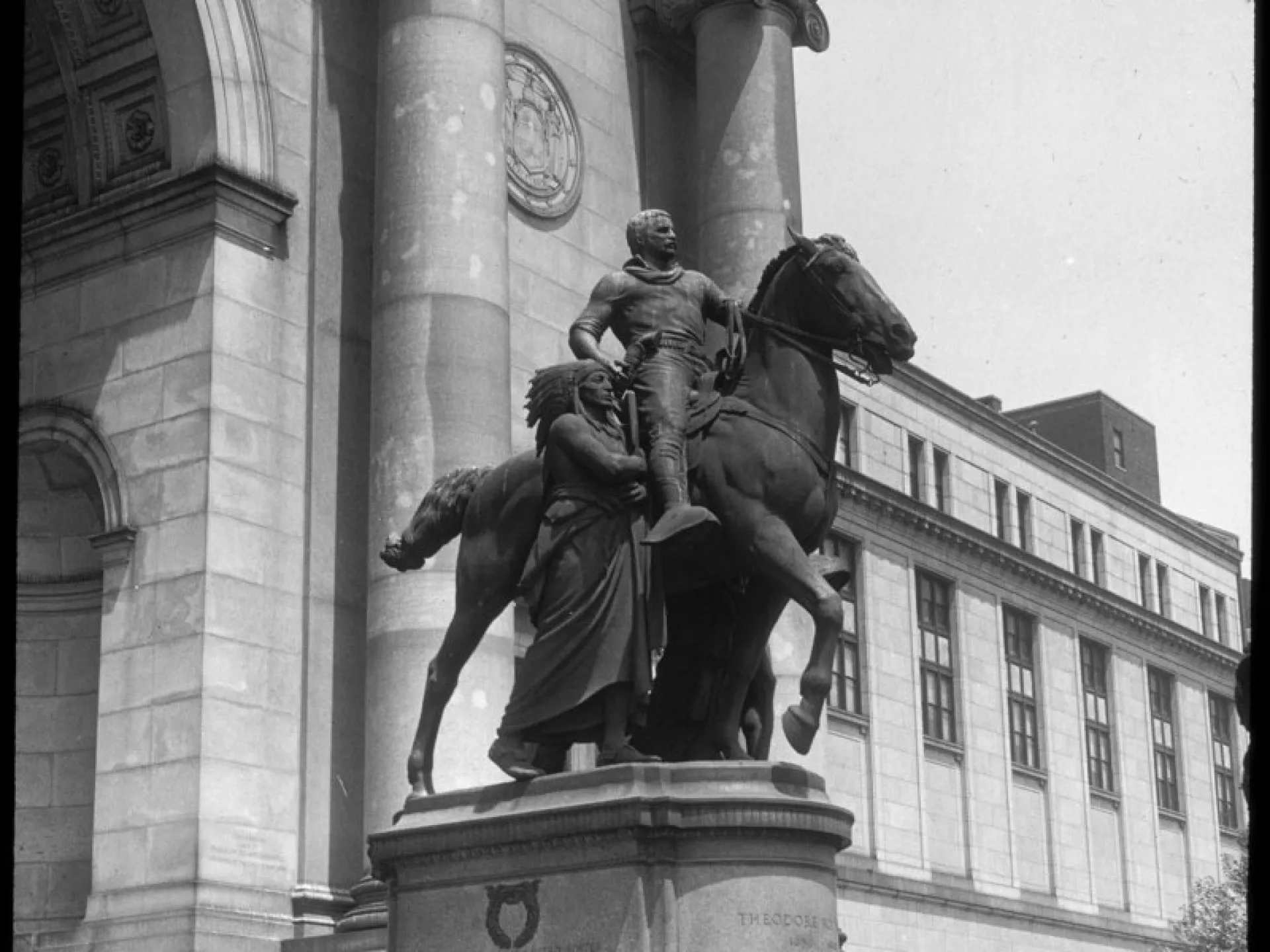 Bronze equestrian statue of Theodore Roosevelt flanked by two standing figures at the entrance of the American Museum of Natural History.