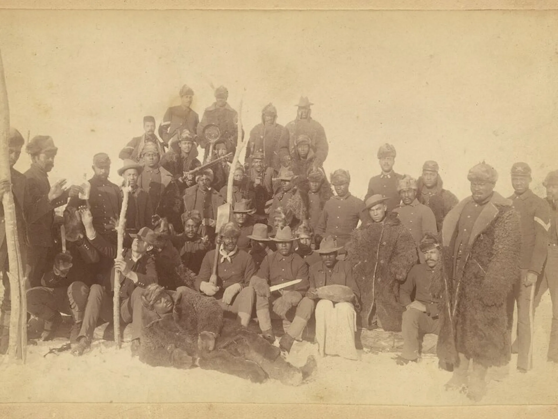 Group photograph of African American soldiers of the 25th Infantry Regiment posed outdoors in winter clothing.