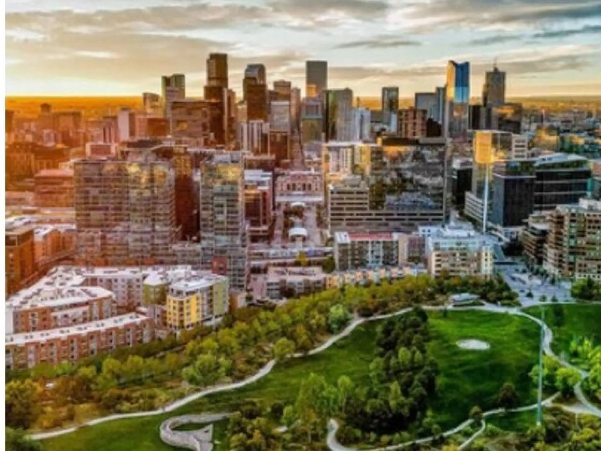 The Denver skyline at sunset above a green city park in Colorado