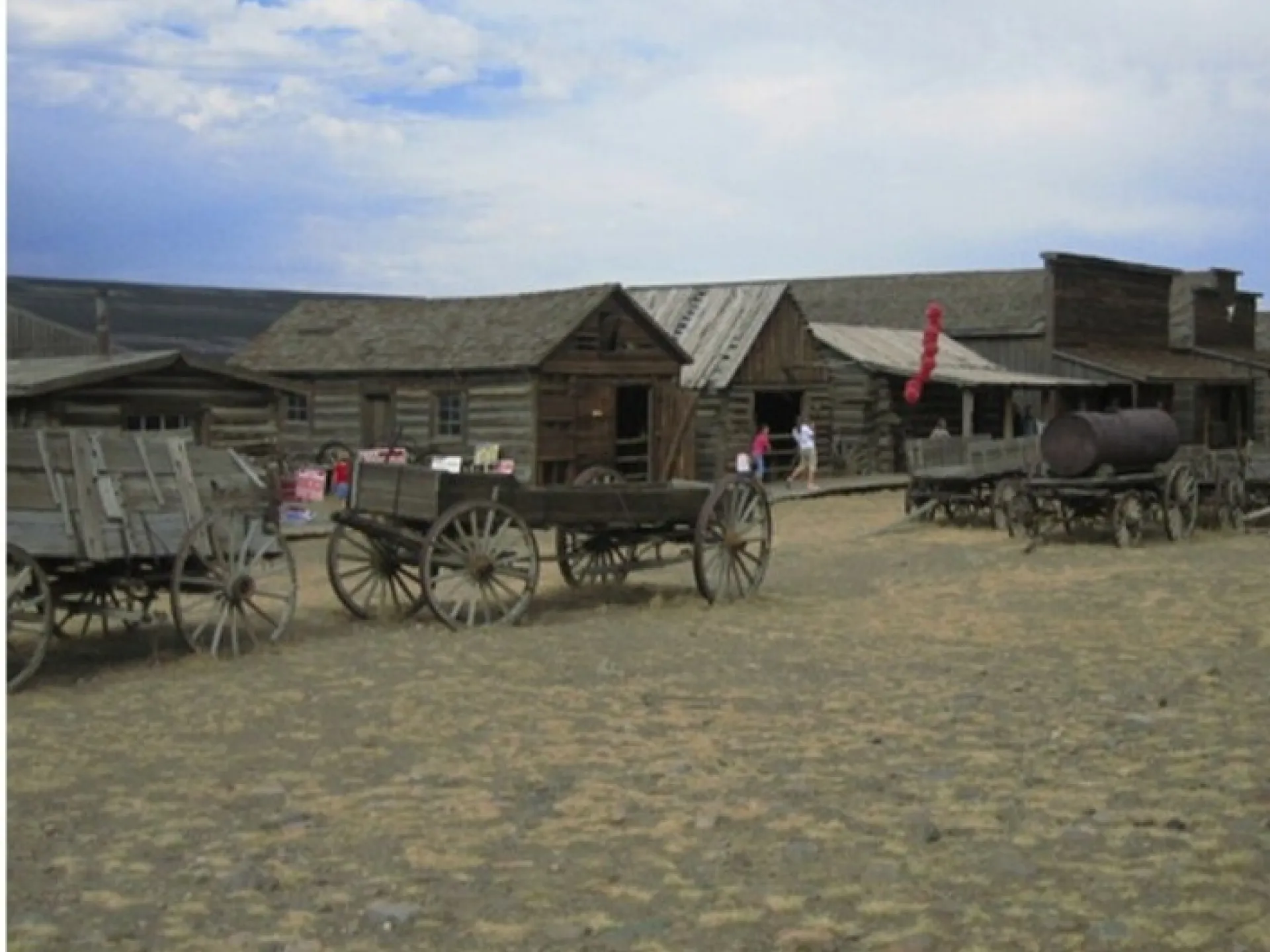 Weathered log cabins and horse-drawn wagons at Old Trail Town, a preserved frontier village in Cody, Wyoming