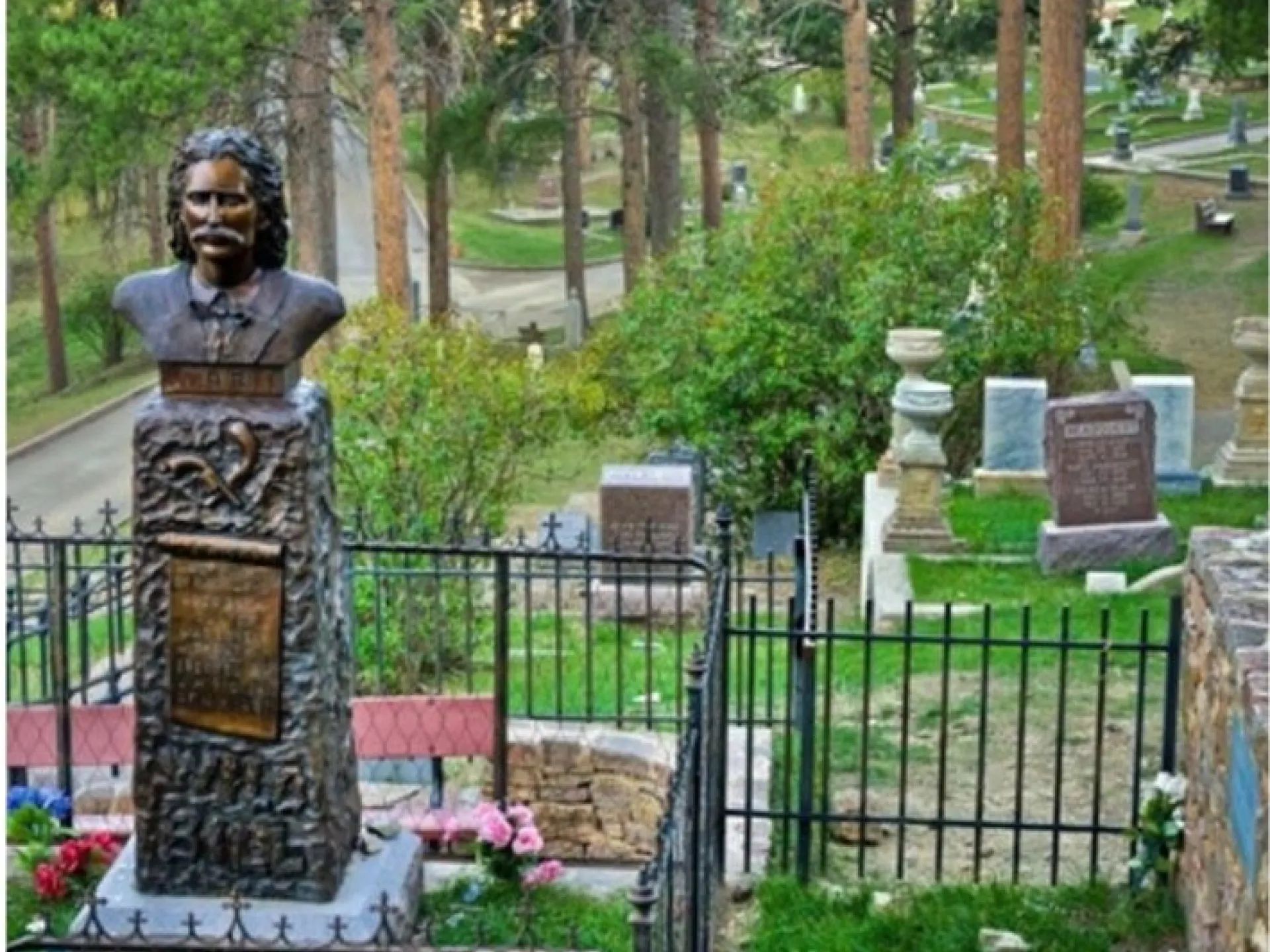 A carved stone monument behind an iron fence at Mount Moriah Cemetery in Deadwood, South Dakota