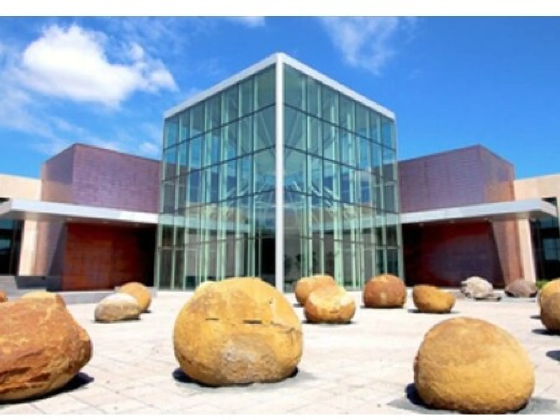 The glass and stone entrance of the North Dakota Heritage Center and State Museum in Bismarck, with large boulders in the plaza