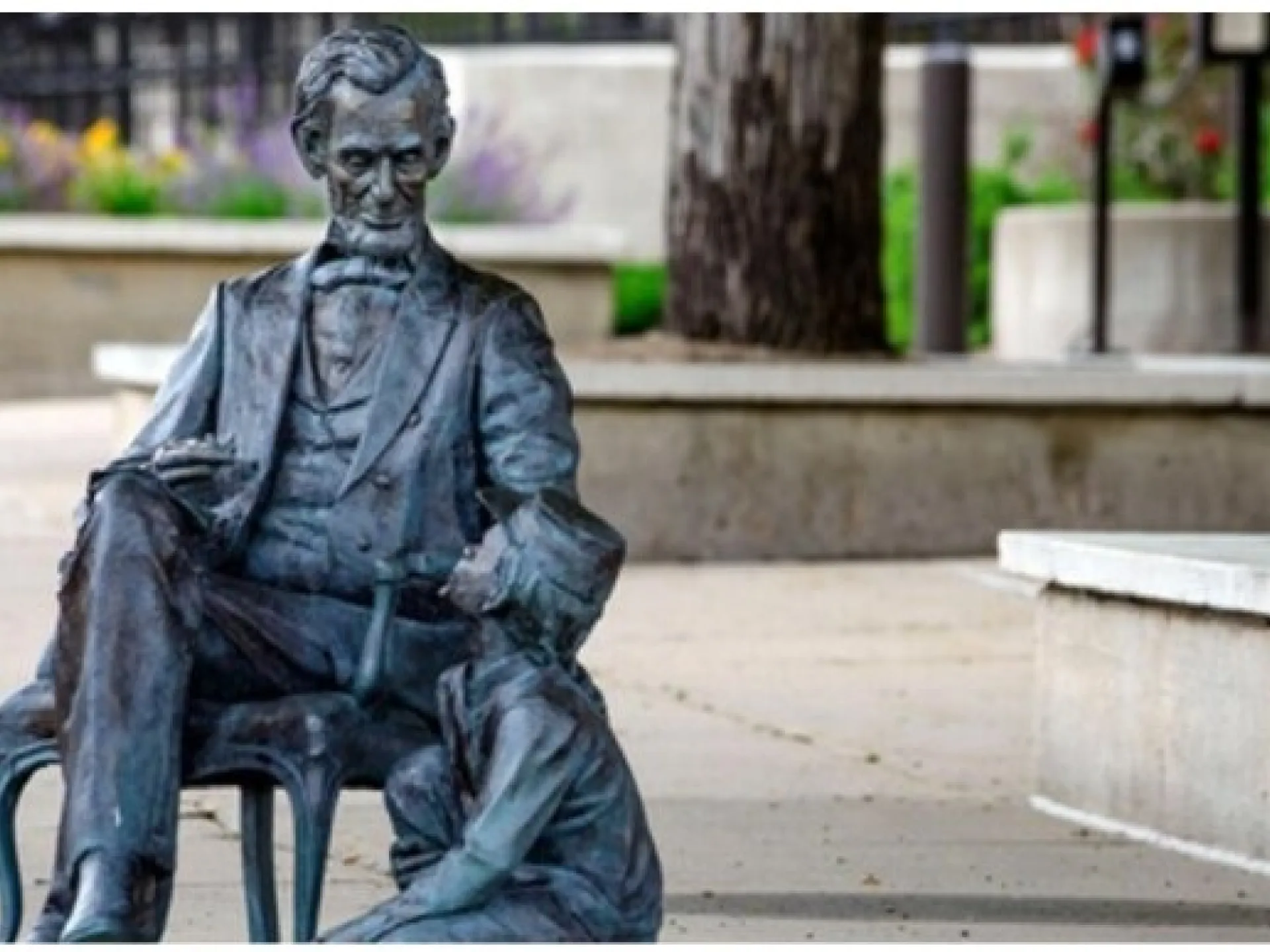 A life-size bronze statue of a seated president on a downtown sidewalk, part of the City of Presidents series in Rapid City, South Dakota