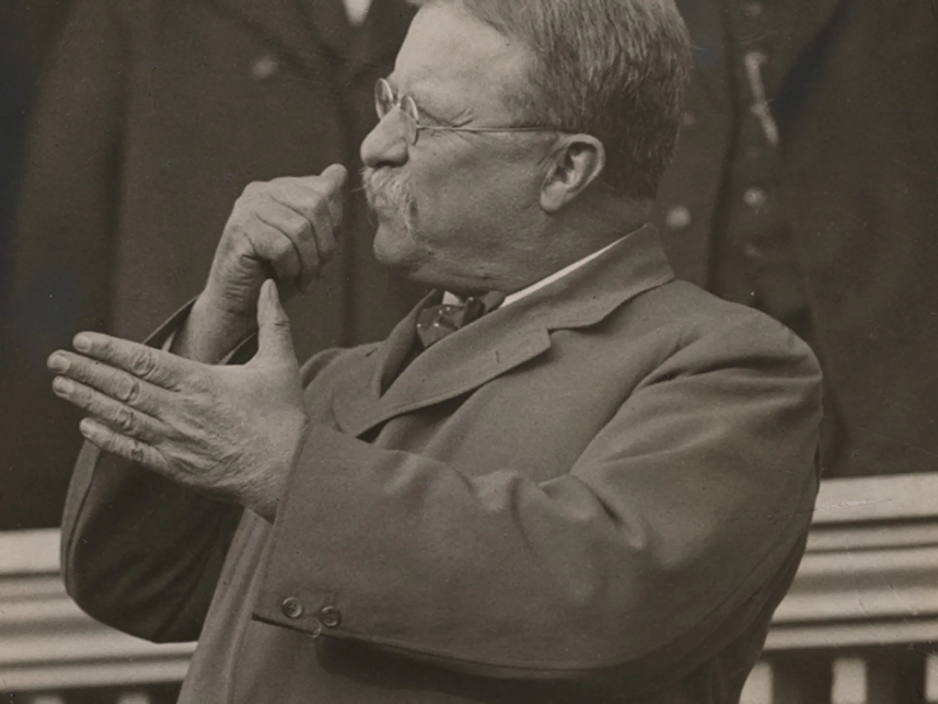 Theodore Roosevelt gesturing with clasped hands while delivering a speech