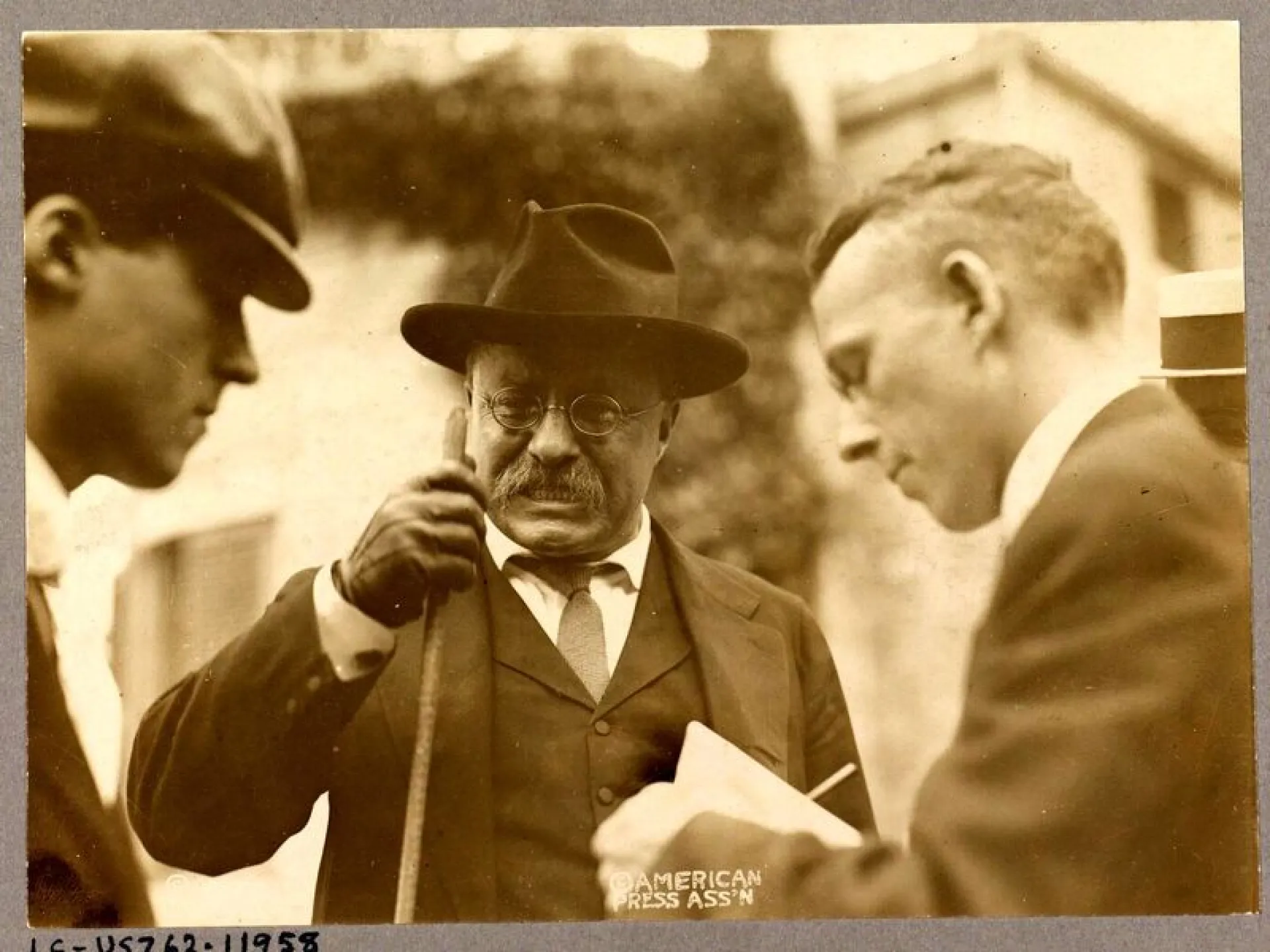 Theodore Roosevelt speaking with newsmen, papers in hand