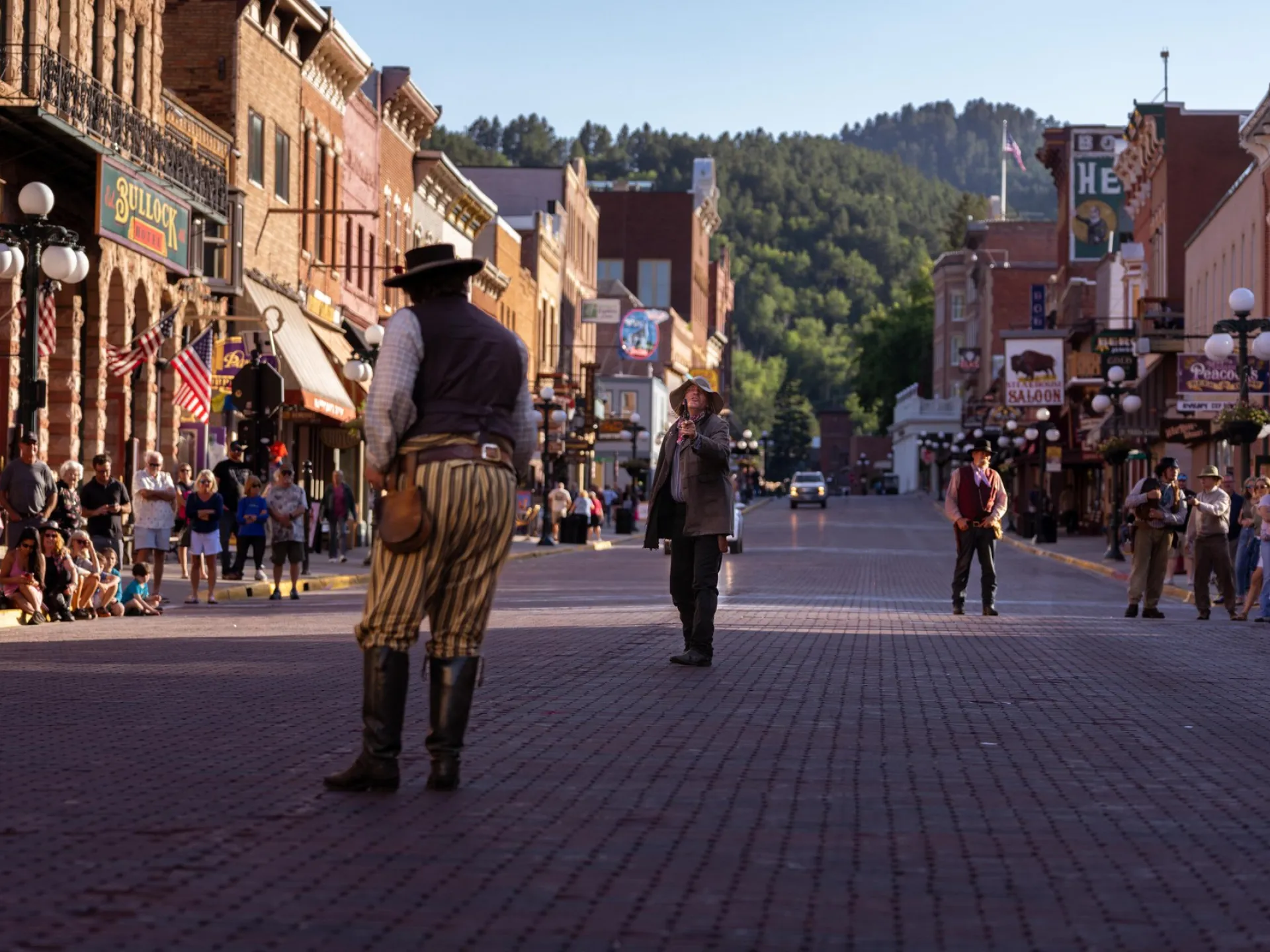 Re-enactors on the brick main street of historic Deadwood, South Dakota, with the Bullock Hotel sign above the crowd