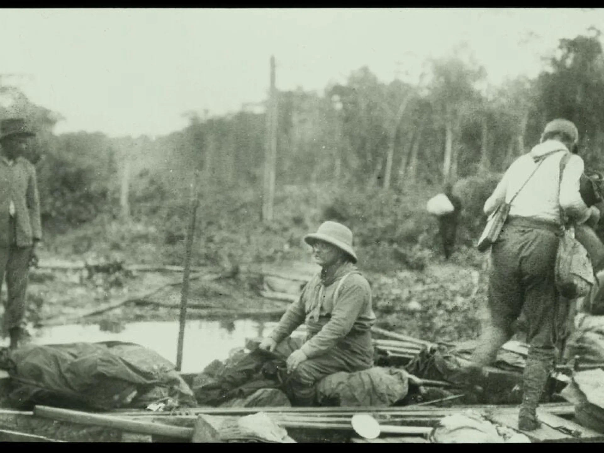 Expedition members with a loaded dugout raft on a jungle river