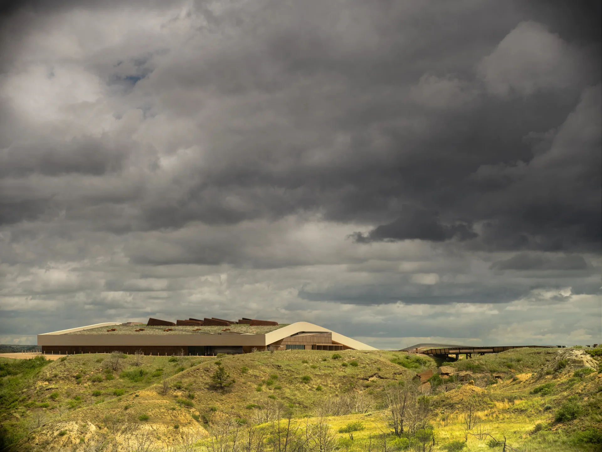 The Theodore Roosevelt Presidential Library on the butte above Medora, with the badlands below and storm clouds overhead