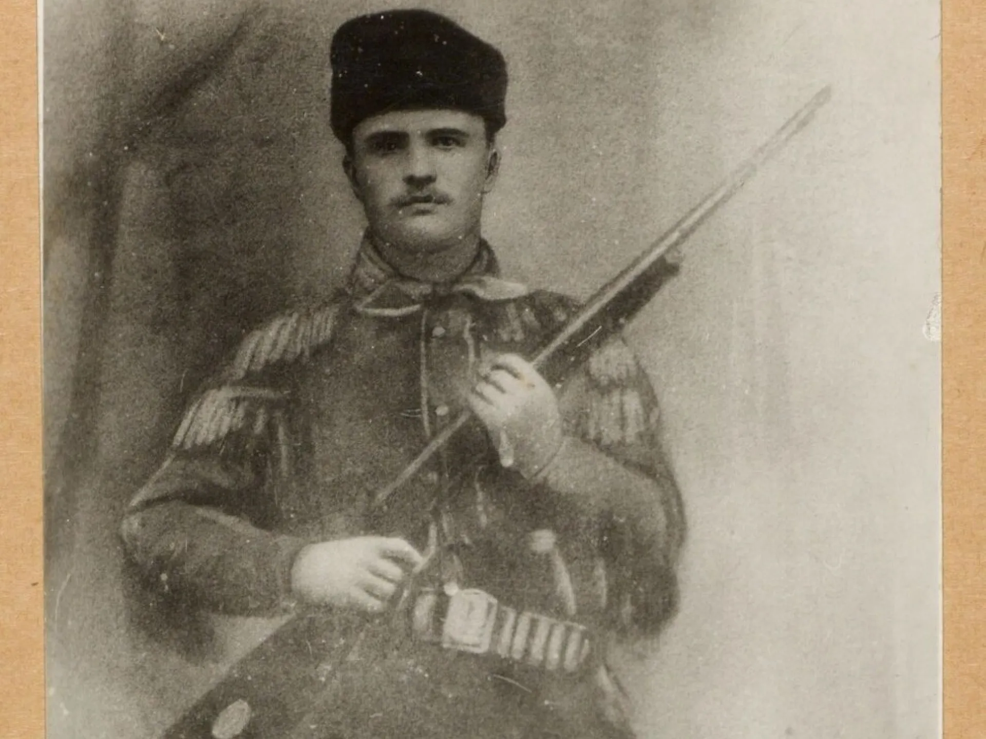 Theodore Roosevelt in a fringed buckskin hunting suit and fur cap, holding a rifle