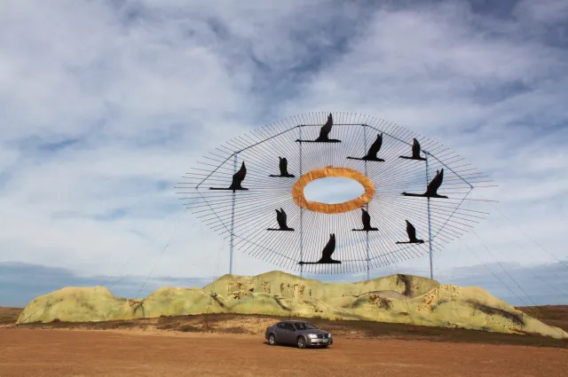 Geese in Flight, the giant scrap metal sculpture at the north end of the Enchanted Highway, with a car parked below for scale