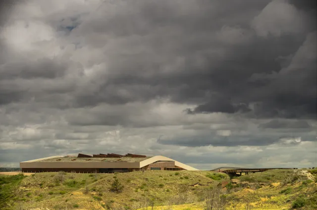 The Theodore Roosevelt Presidential Library on the butte above Medora, with the badlands below and storm clouds overhead