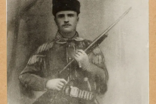Theodore Roosevelt in a fringed buckskin hunting suit and fur cap, holding a rifle