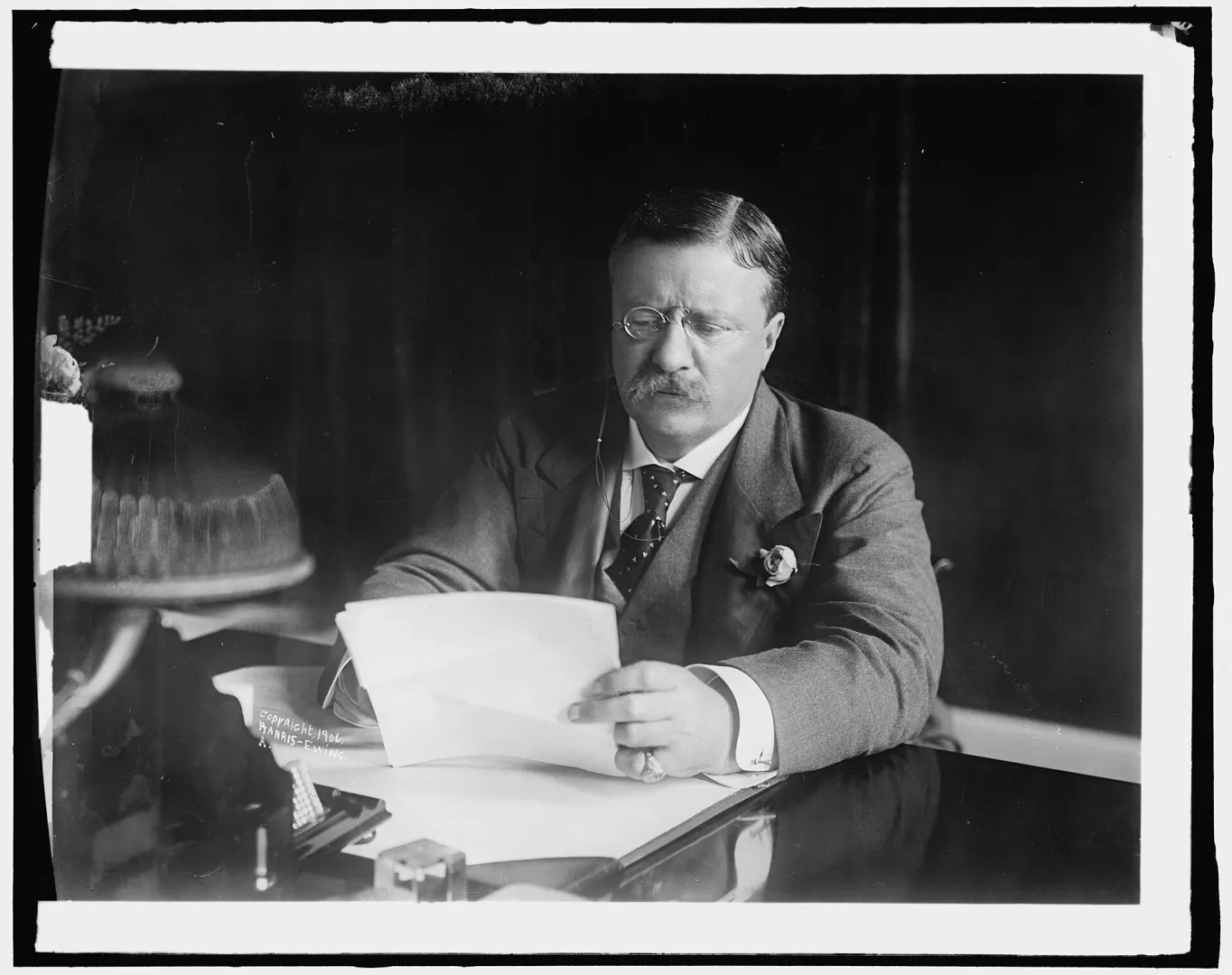 President Theodore Roosevelt seated at his desk reading a document