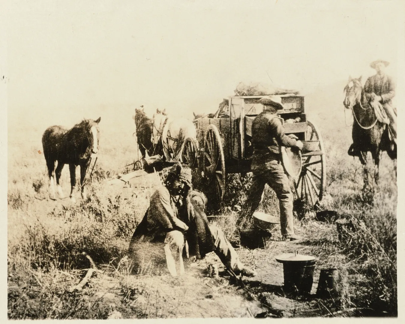 Cowboys, horses, and a chuck wagon at a roundup camp on the open prairie