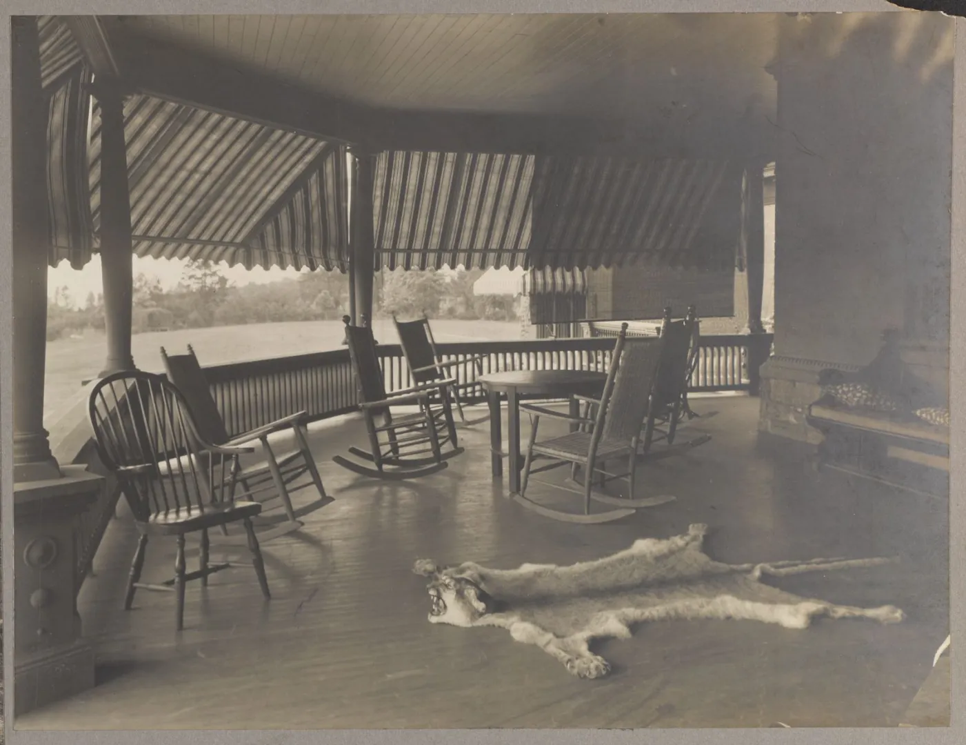 The piazza at Sagamore Hill with rocking chairs and an animal-skin rug, overlooking Oyster Bay