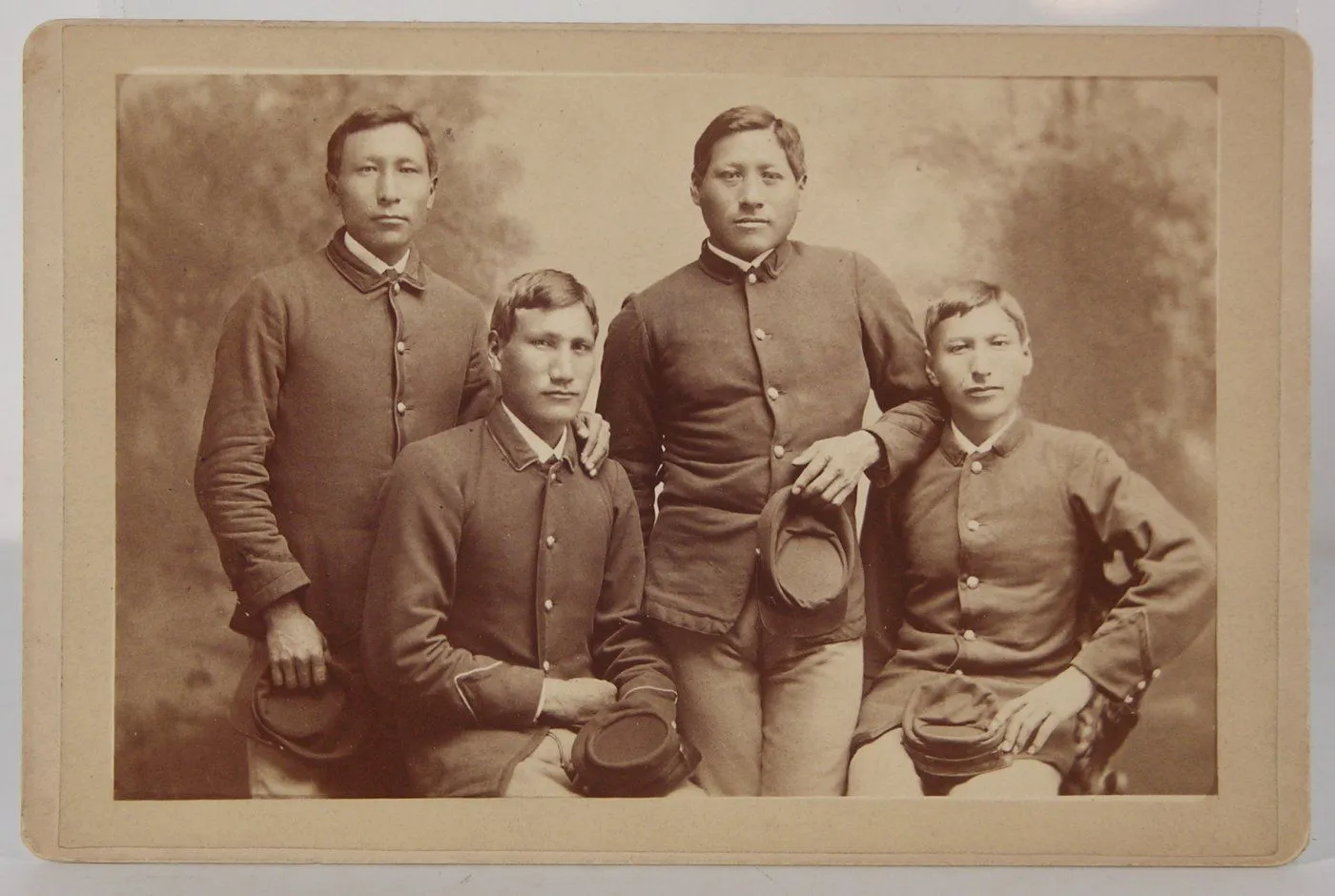 Cabinet-card portrait of four Native American students in uniform at the Carlisle Indian Industrial School, 1879