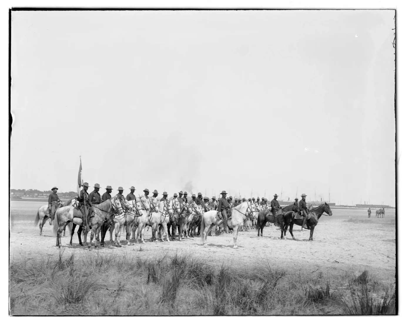 A line of Black cavalry troopers on horseback formed up on flat open ground, 1898
