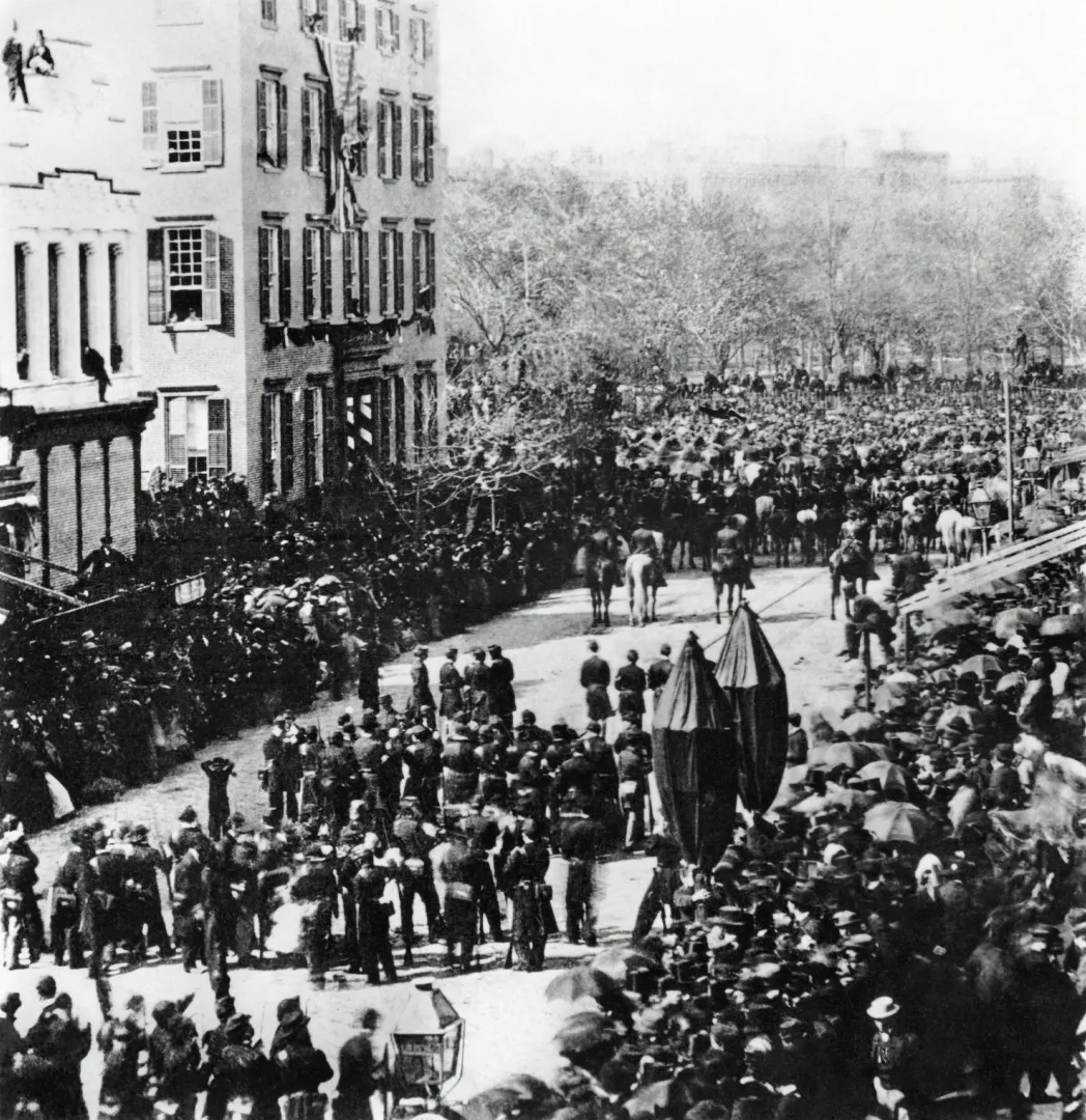Abraham Lincoln’s funeral procession moving up Broadway past a corner mansion amid an enormous crowd