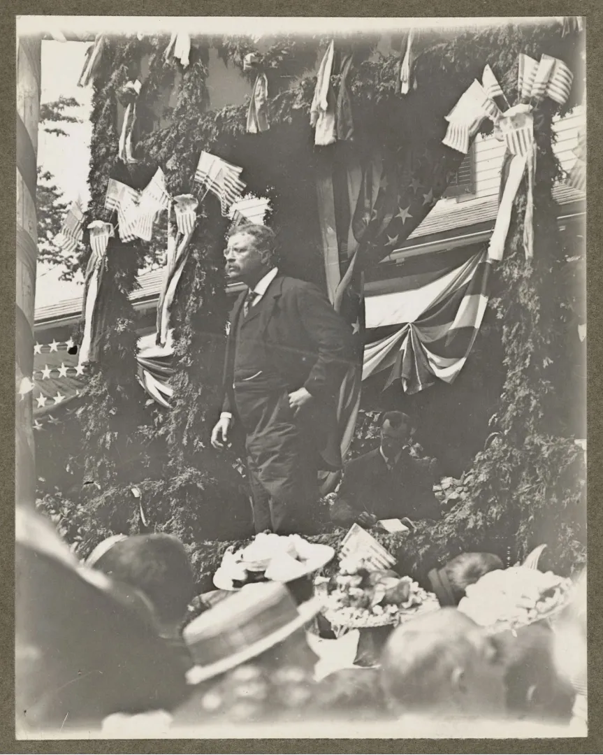 Theodore Roosevelt speaking from a bunting-draped platform to a crowd during the 1912 campaign