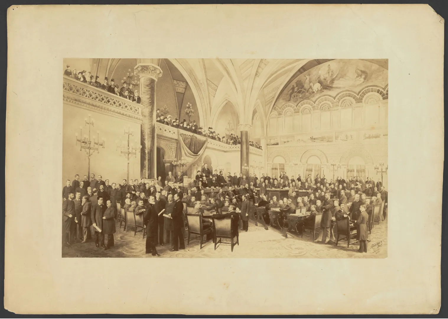 Sepia photograph of legislators gathered in the ornate New York State Assembly chamber