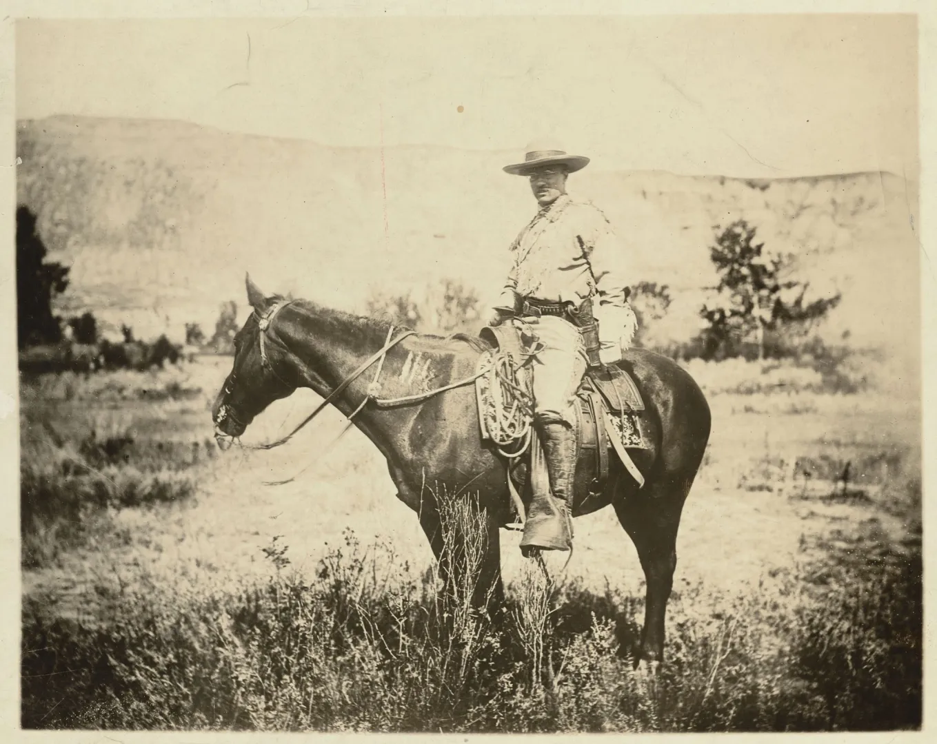 Theodore Roosevelt in ranch clothing mounted on horseback in the Dakota Badlands