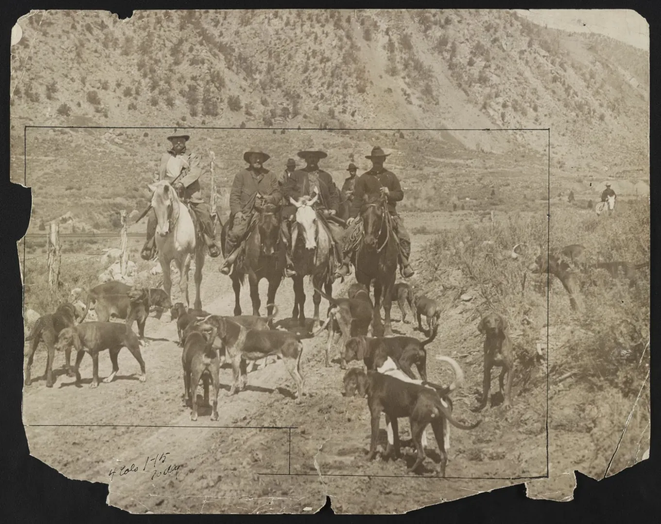 Theodore Roosevelt and other men on horseback with a pack of hunting dogs in open western country.