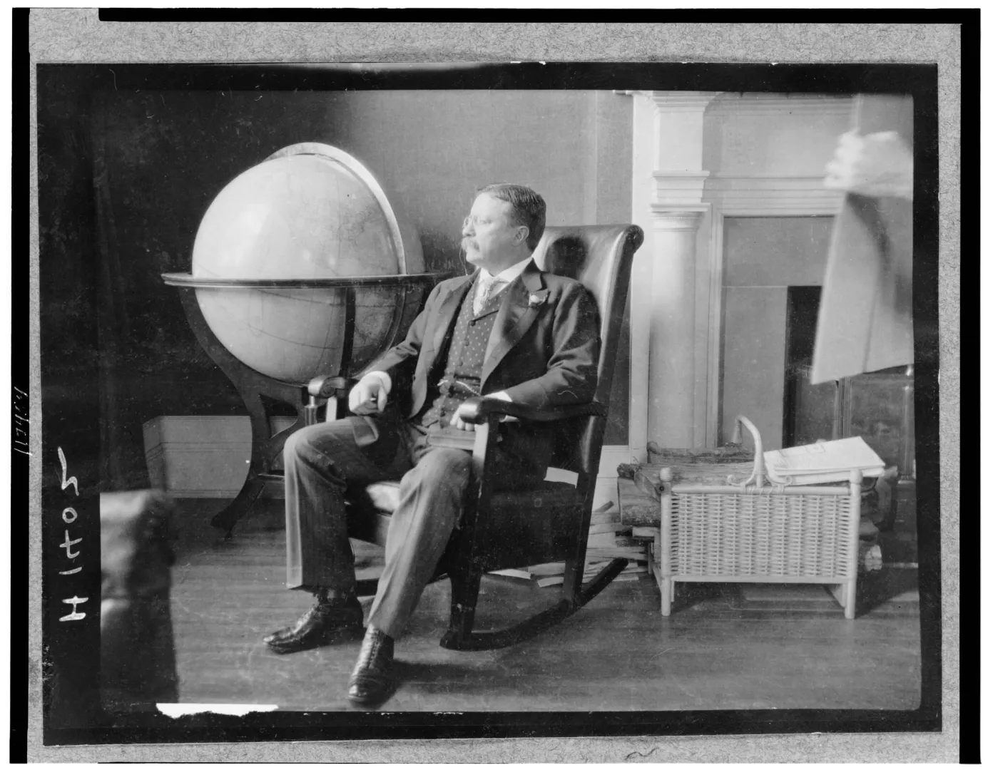 Theodore Roosevelt seated beside a large globe