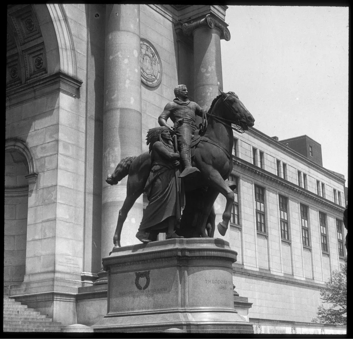 Bronze statue of Theodore Roosevelt on horseback flanked by two standing figures at a museum entrance