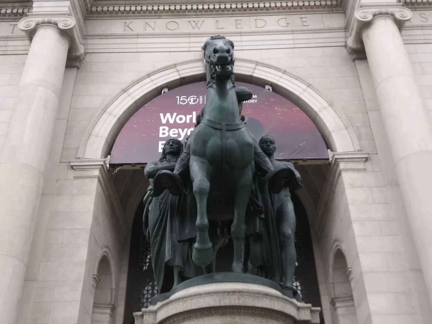 Color photograph of the Roosevelt equestrian statue with the mounted figure above two men standing on foot