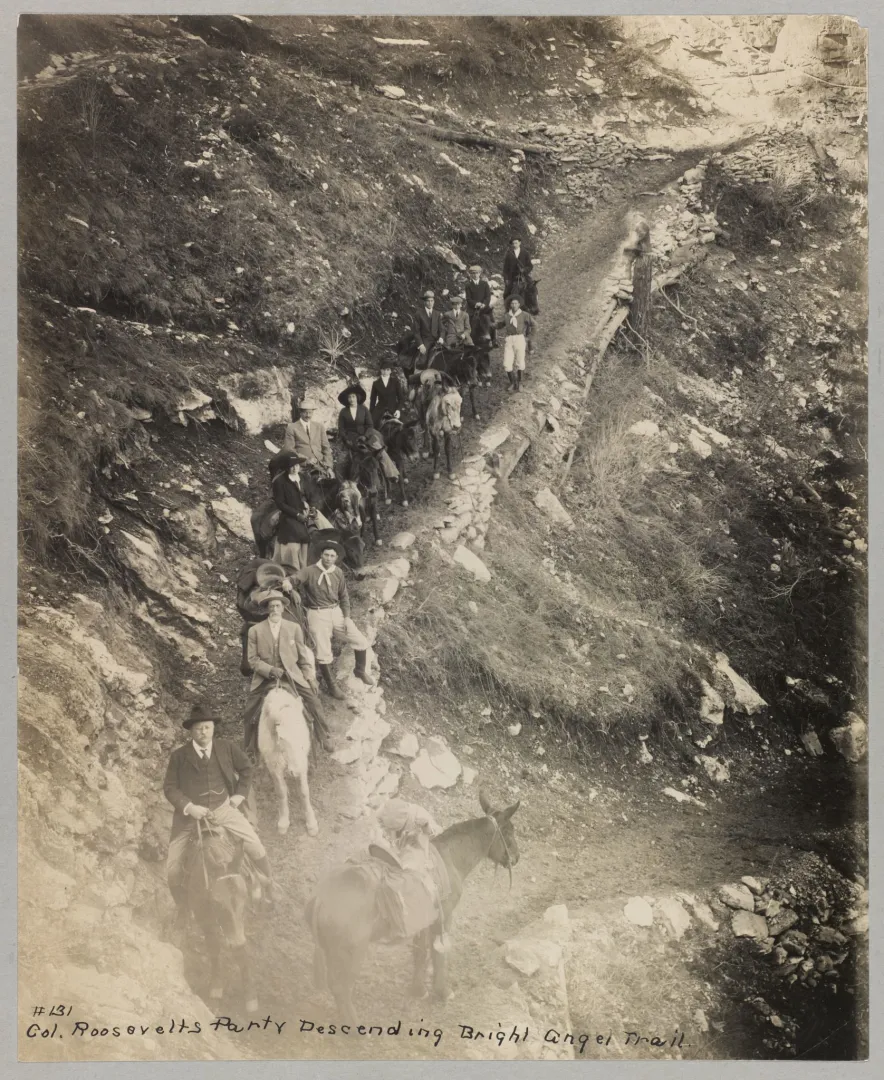 A line of people descending a steep switchback trail into the Grand Canyon