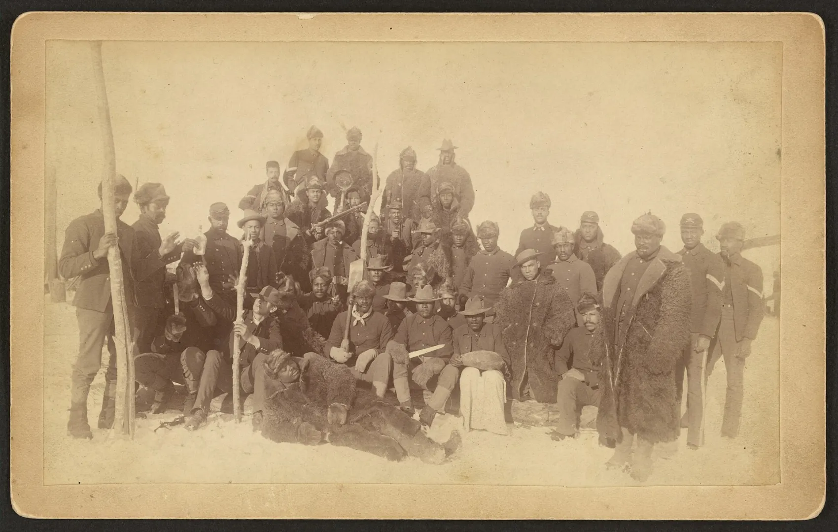 Historic group photograph of African American soldiers of the 25th Infantry Regiment posed outdoors.