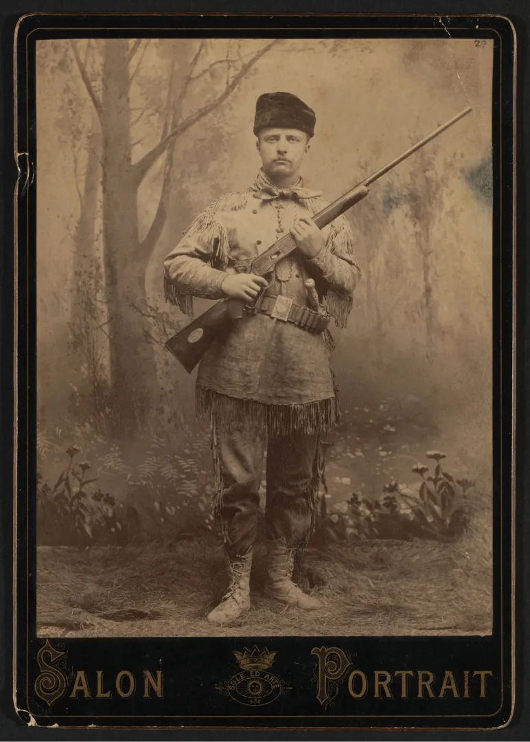 Theodore Roosevelt in buckskin standing guard with his rifle