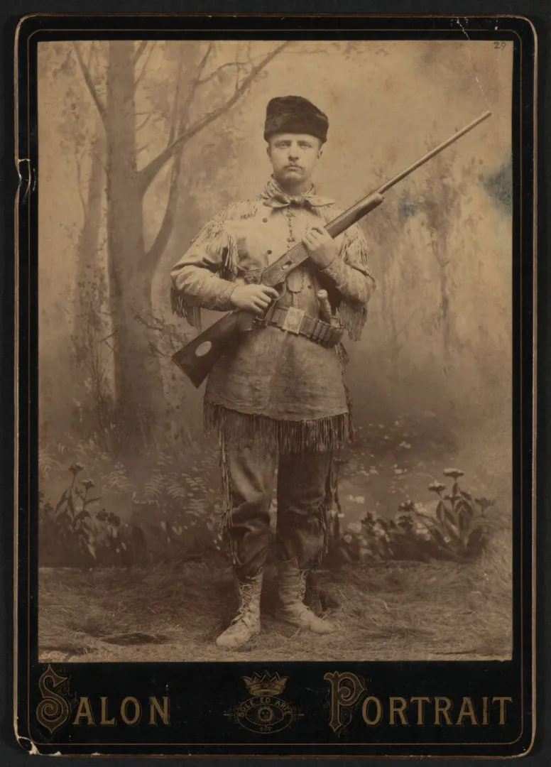 Theodore Roosevelt in a buckskin hunting suit with a rifle