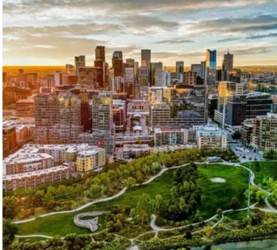 The Denver skyline at sunset above a green city park in Colorado