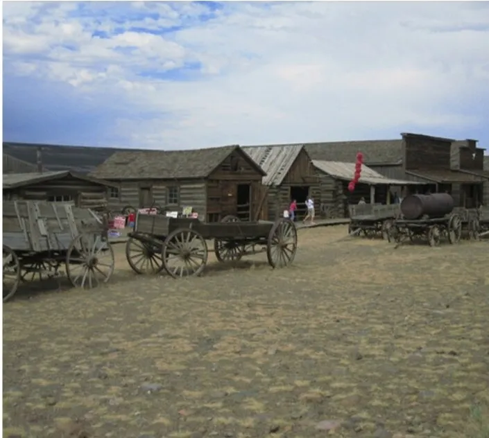 Weathered log cabins and horse-drawn wagons at Old Trail Town, a preserved frontier village in Cody, Wyoming