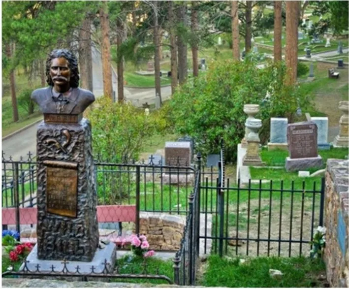 A carved stone monument behind an iron fence at Mount Moriah Cemetery in Deadwood, South Dakota