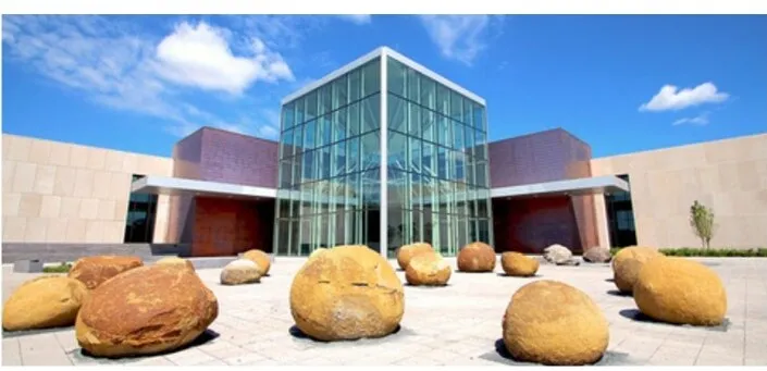 The glass and stone entrance of the North Dakota Heritage Center and State Museum in Bismarck, with large boulders in the plaza