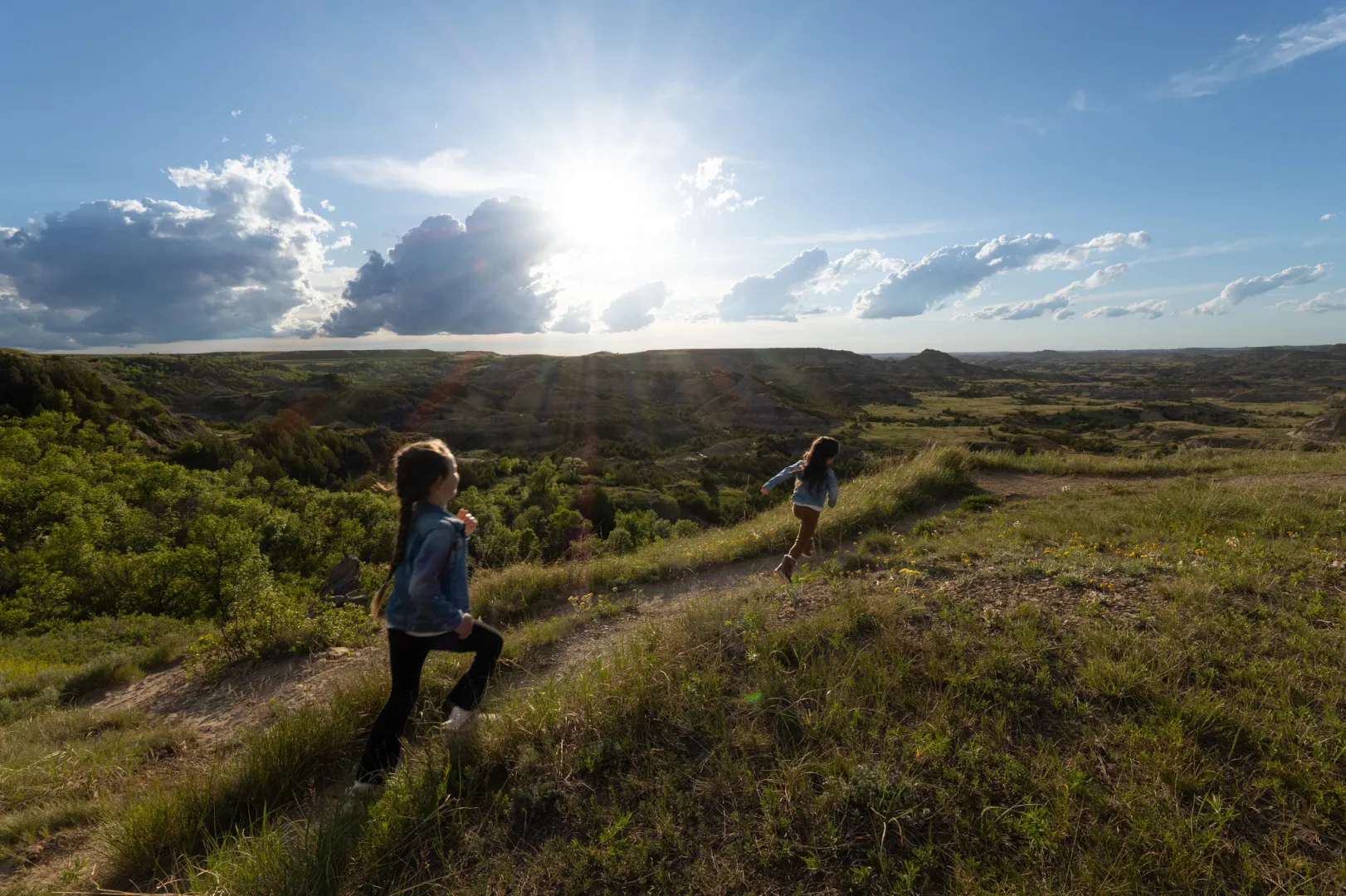 Two children hiking a trail at Painted Canyon in Theodore Roosevelt National Park at sunset