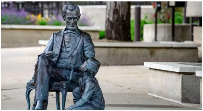 A life-size bronze statue of a seated president on a downtown sidewalk, part of the City of Presidents series in Rapid City, South Dakota