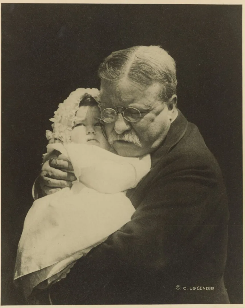 An older Theodore Roosevelt tenderly cradling his infant granddaughter