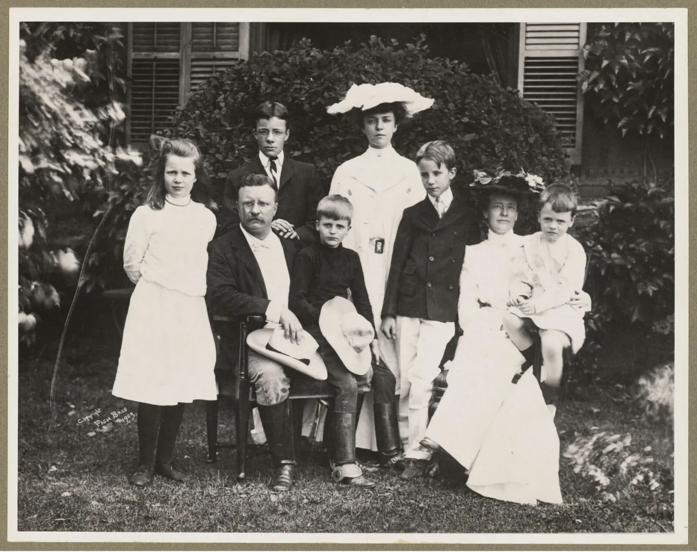 Theodore Roosevelt seated among his children and family outdoors at Oyster Bay