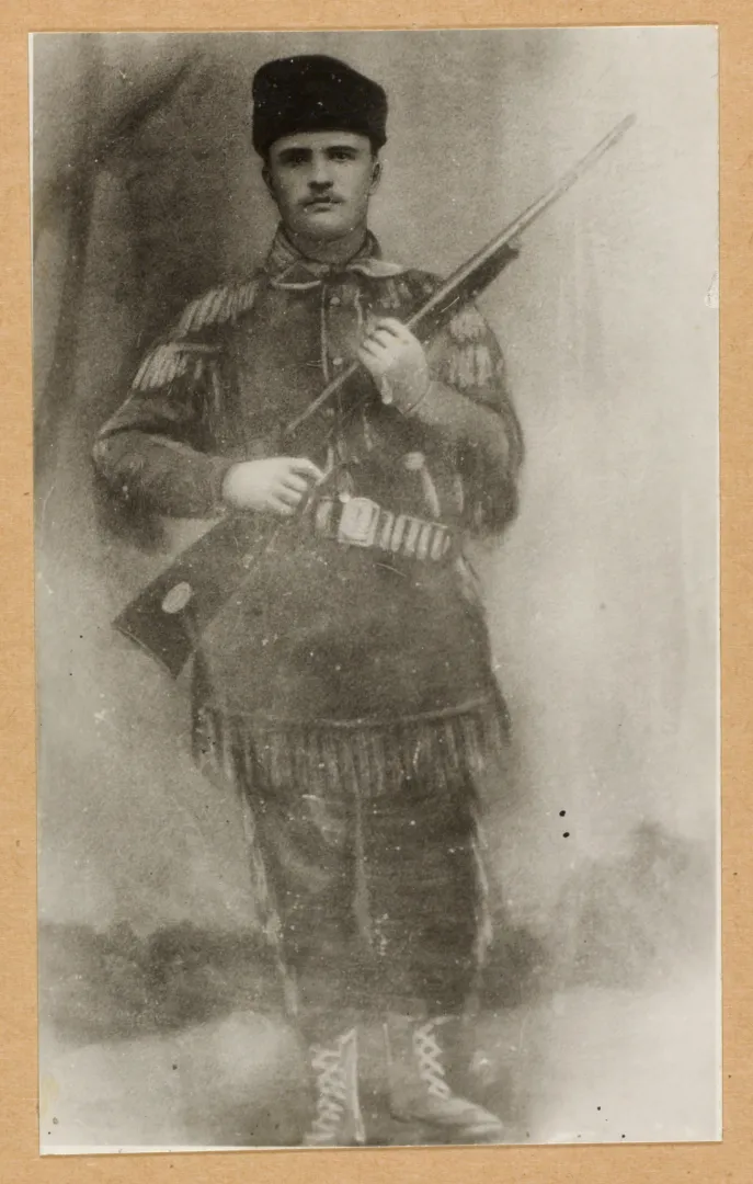 Theodore Roosevelt in a fringed buckskin hunting suit holding a rifle, about 1885
